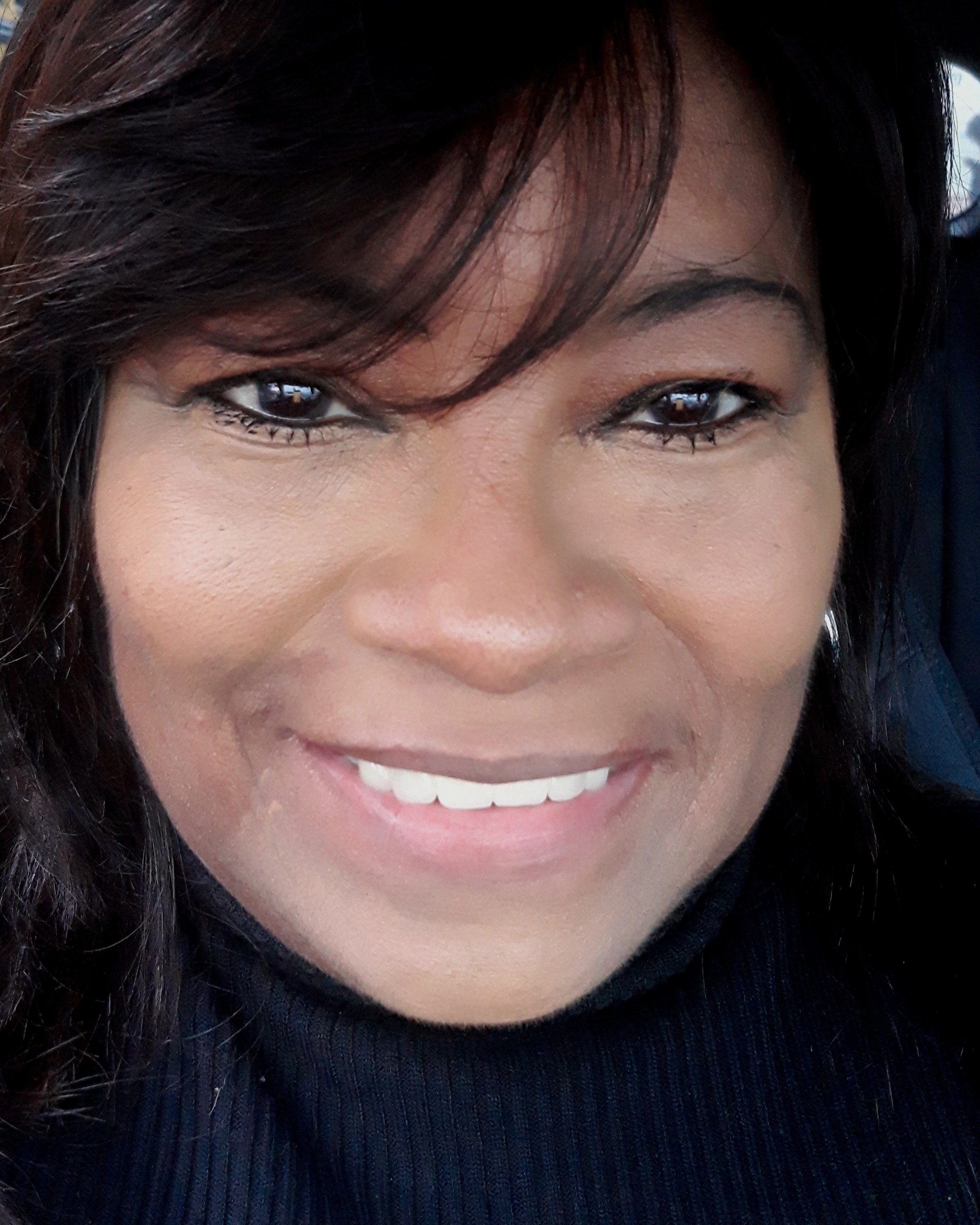 Close-up of a smiling woman with dark hair and wearing a black top.