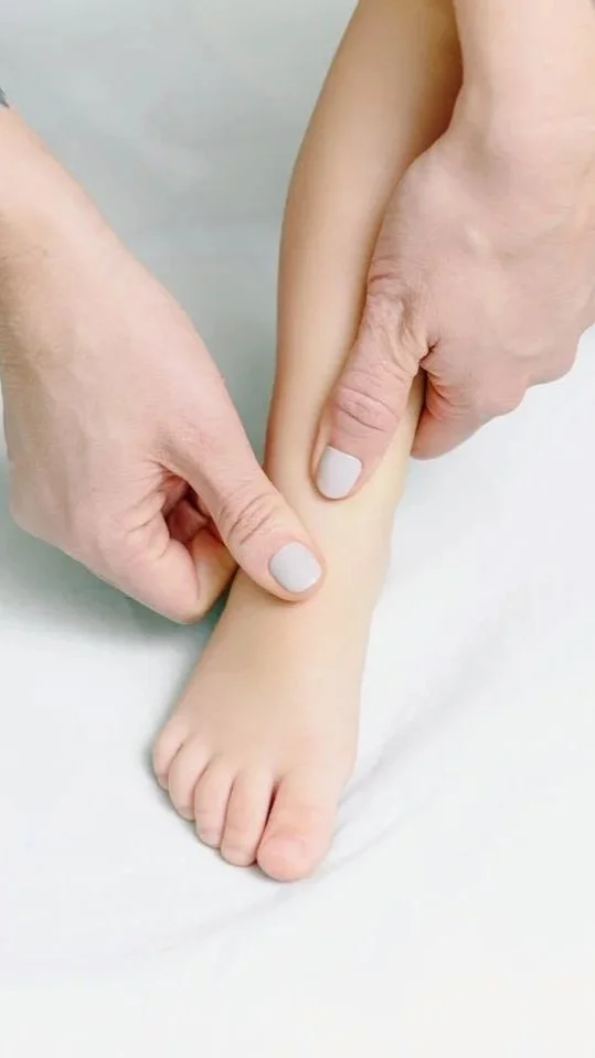 Close-up of a person applying gentle pressure on a child’s foot with their fingers.