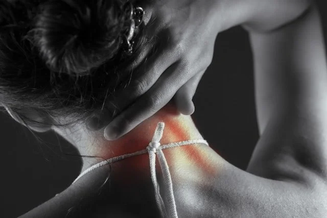 A person holding their neck, which appears inflamed or sore, with a red area and a white cord tied around the neck.
