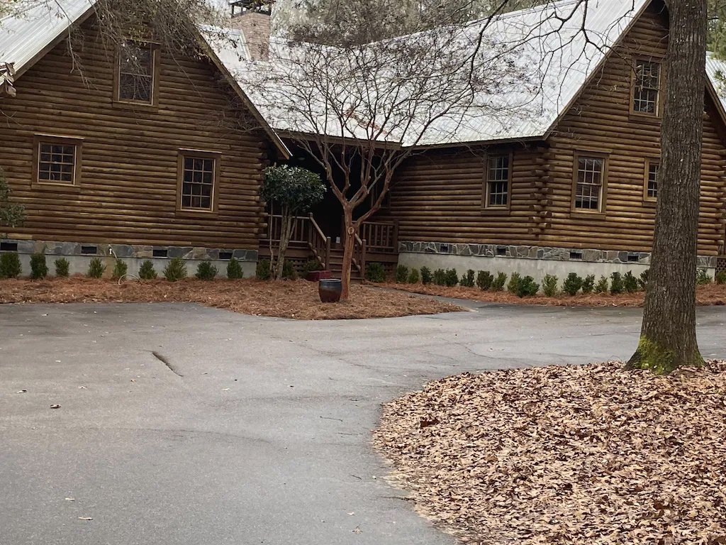A white pickup truck driving along a rugged dirt path through a vast, dry African landscape with sparse bushes and trees stretching toward the horizon.
