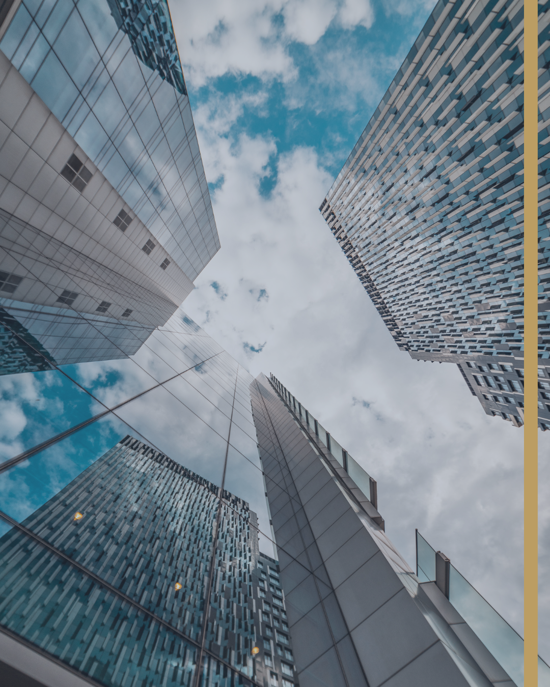 Low-angle view of modern glass skyscrapers against a cloudy sky.