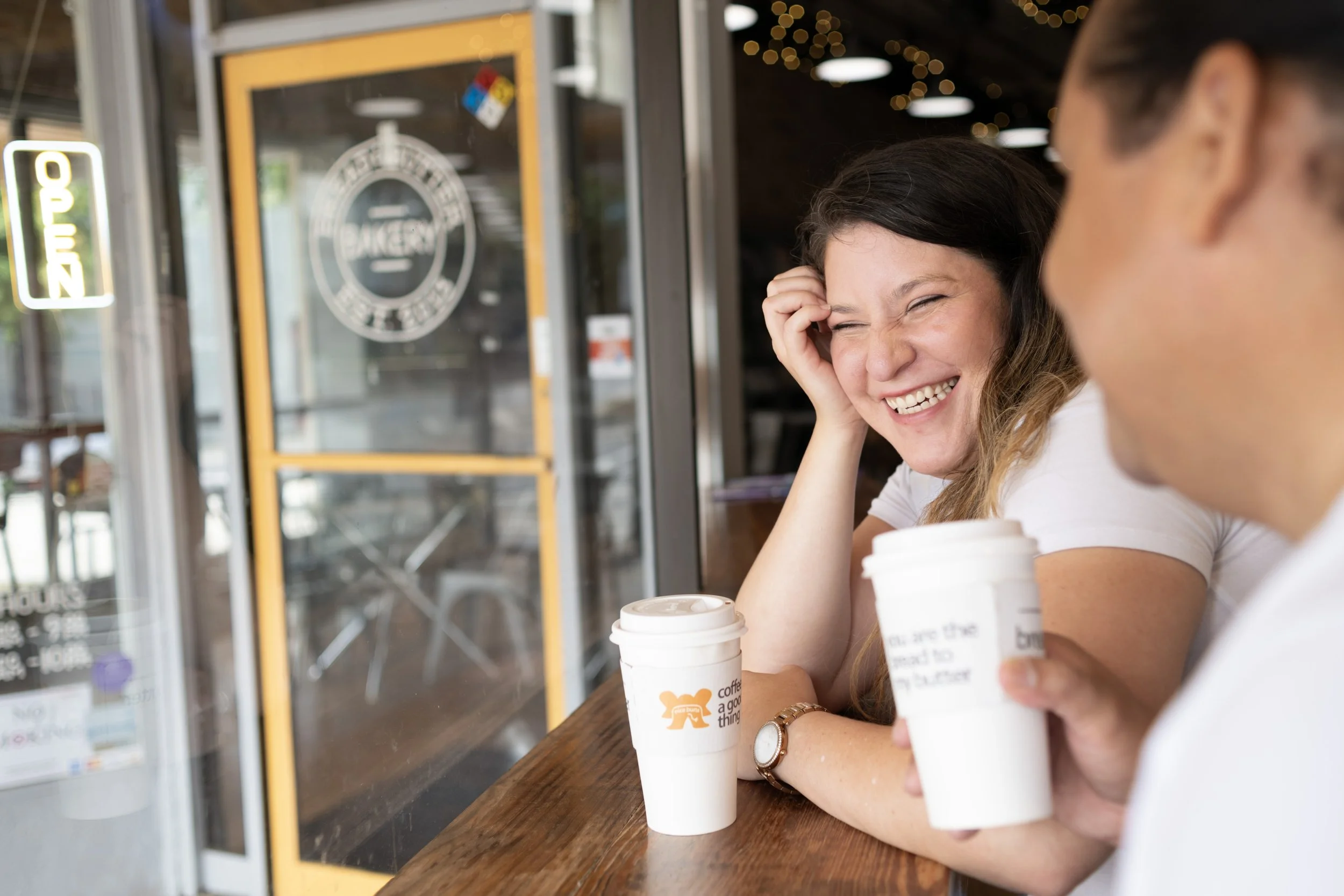 Smiling woman drinking coffee at Bread and Butter in Covington Georgia with her partner in Lifestyle Photography for couples.