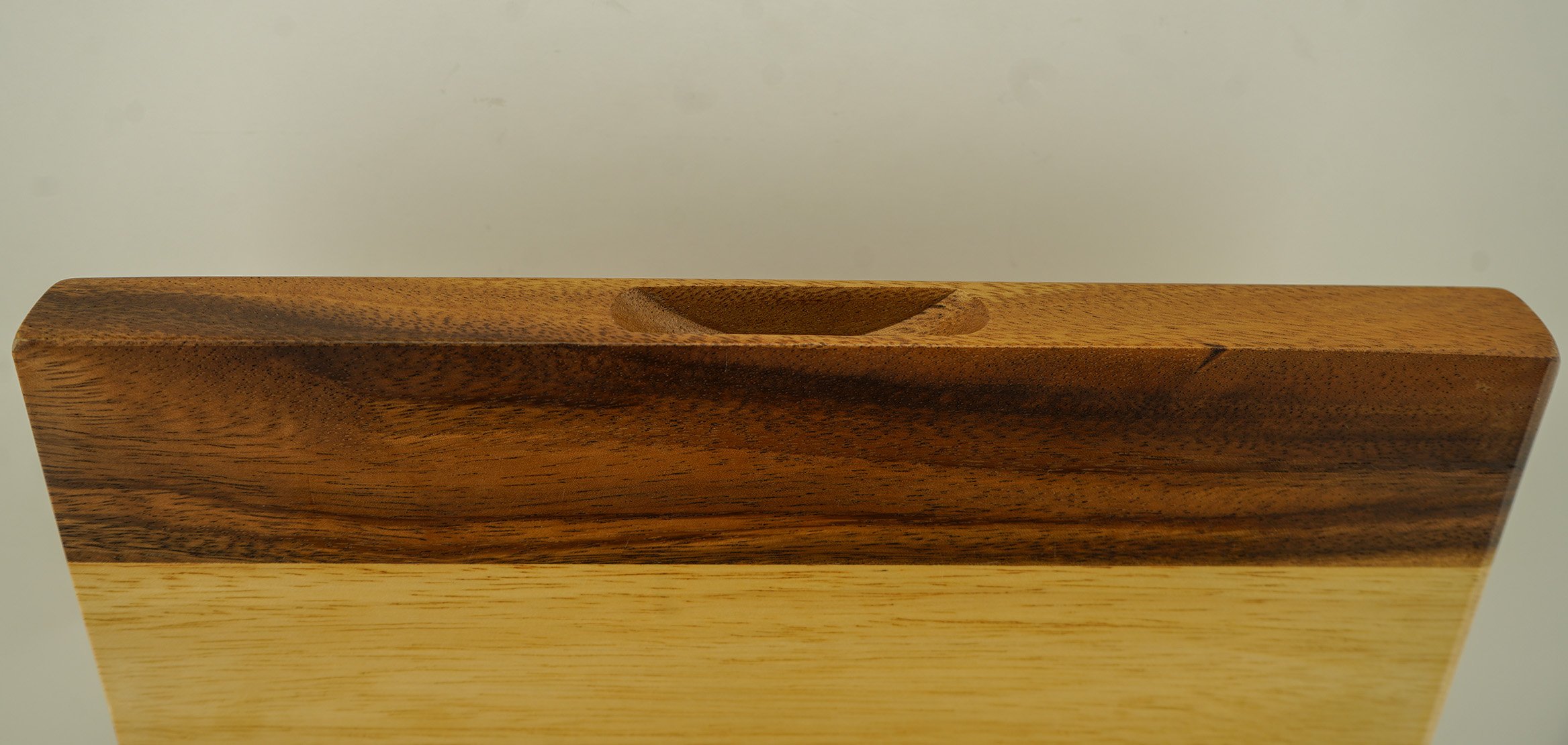 Close-up of a wooden desk organizer with a carved compartment on top, against a plain background.