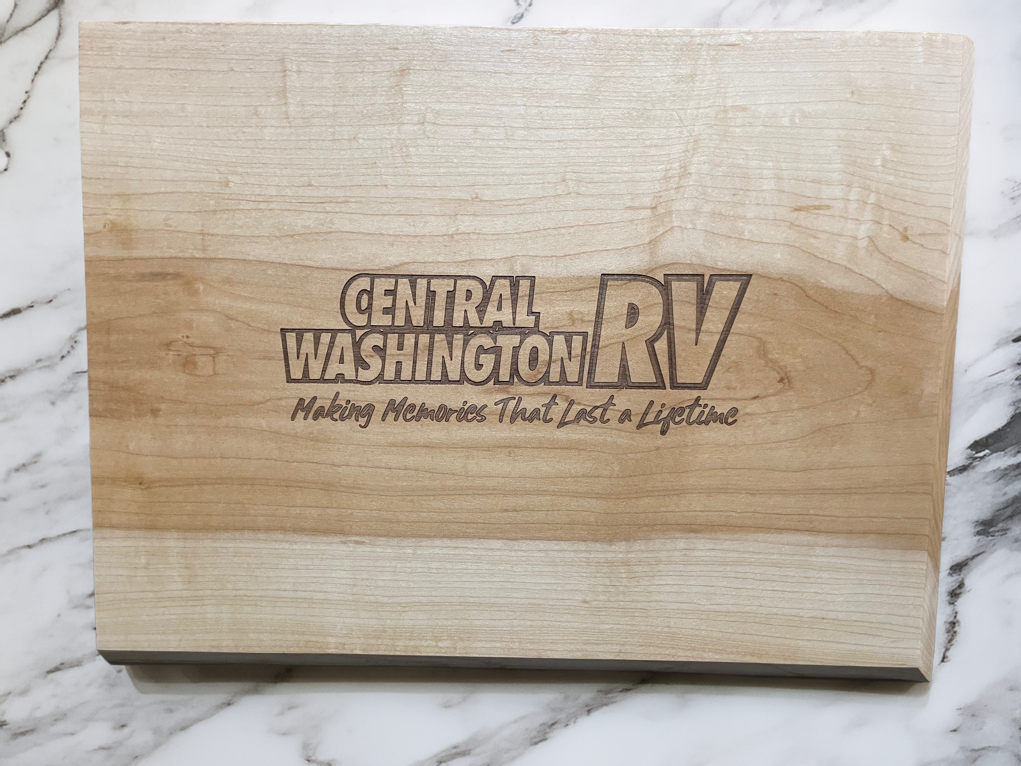 A wooden plaque with the words "Central Washington RV" and the slogan "Making Memories That Last a Lifetime" engraved on it, resting on a marble surface.