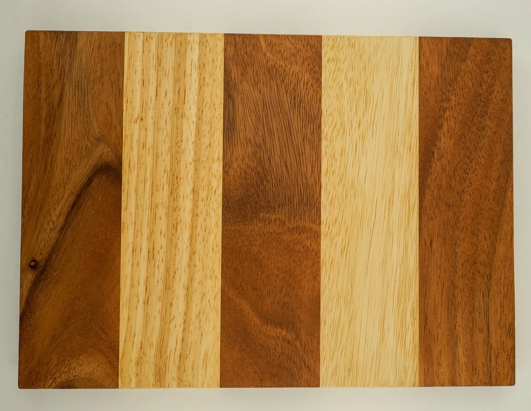 A rectangular wooden cutting board with alternating light and dark wood stripes.