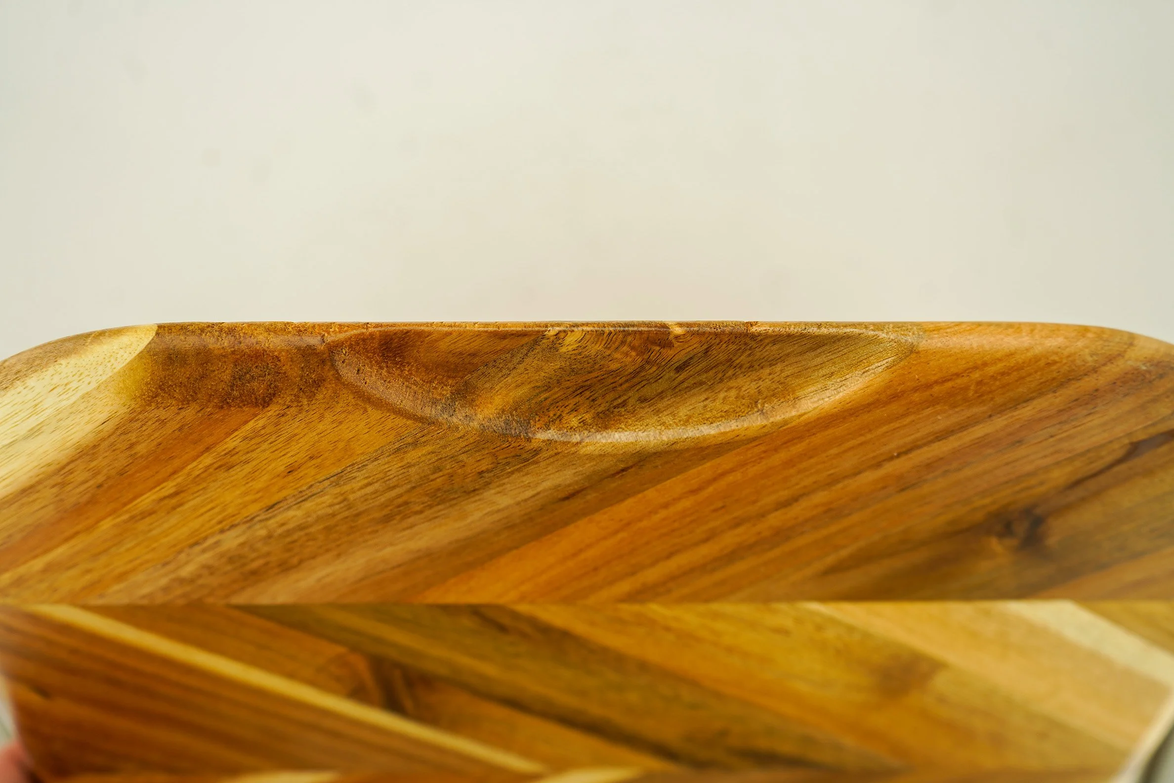 Close-up of a wooden bowl with a natural finish, showing the grain and texture of the wood.