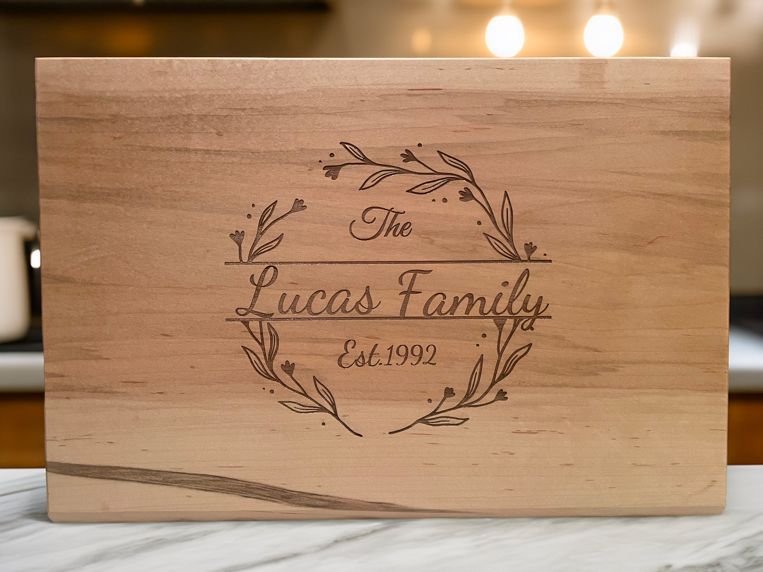 Wooden keepsake box with engraved text reading 'The Lucas Family Est. 1992' surrounded by decorative leaves and hearts.