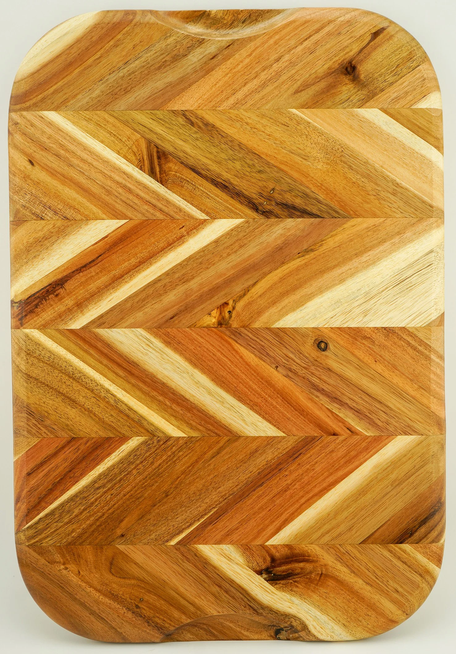 A rectangular wooden cutting board with rounded edges, featuring a pattern of diagonal wood grain sections in various shades of brown.