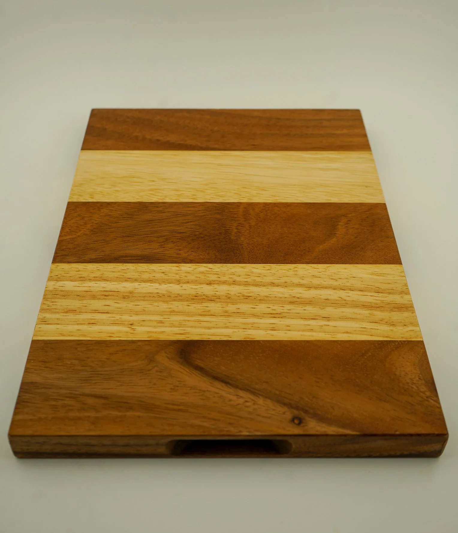A rectangular wooden board with alternating light and dark wood stripes.