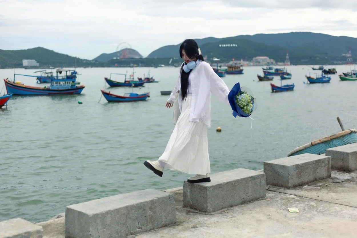 Young woman in white stepping on blocks on a boat quay