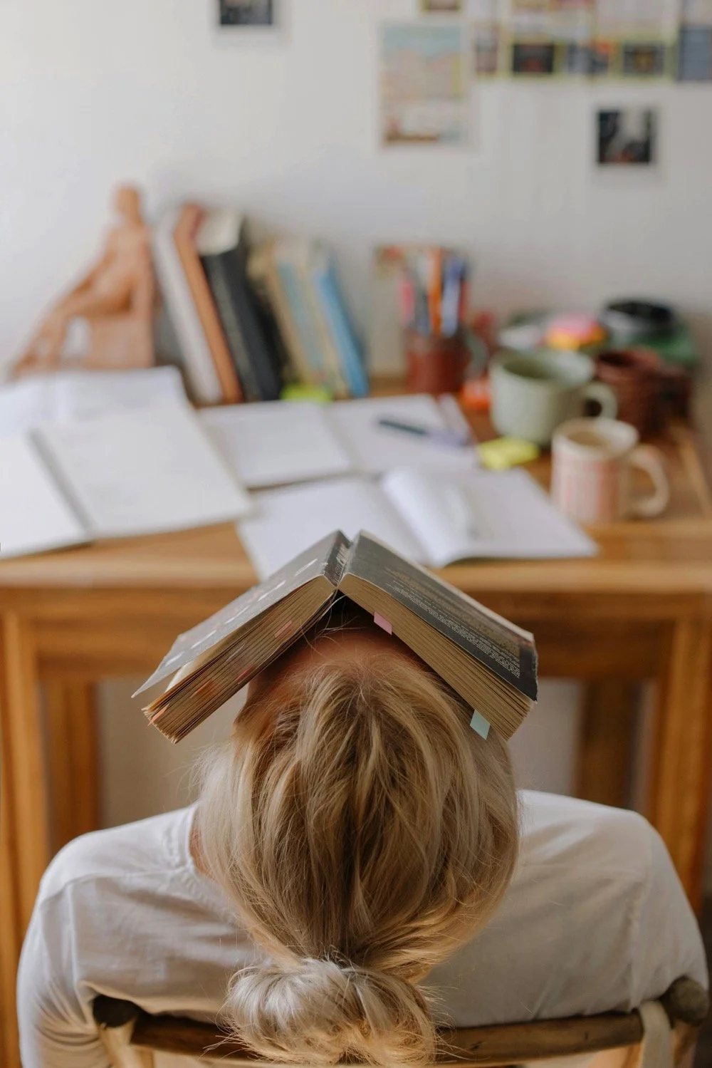 A boarding school pupil with a book on her head with a desk and study material in the background