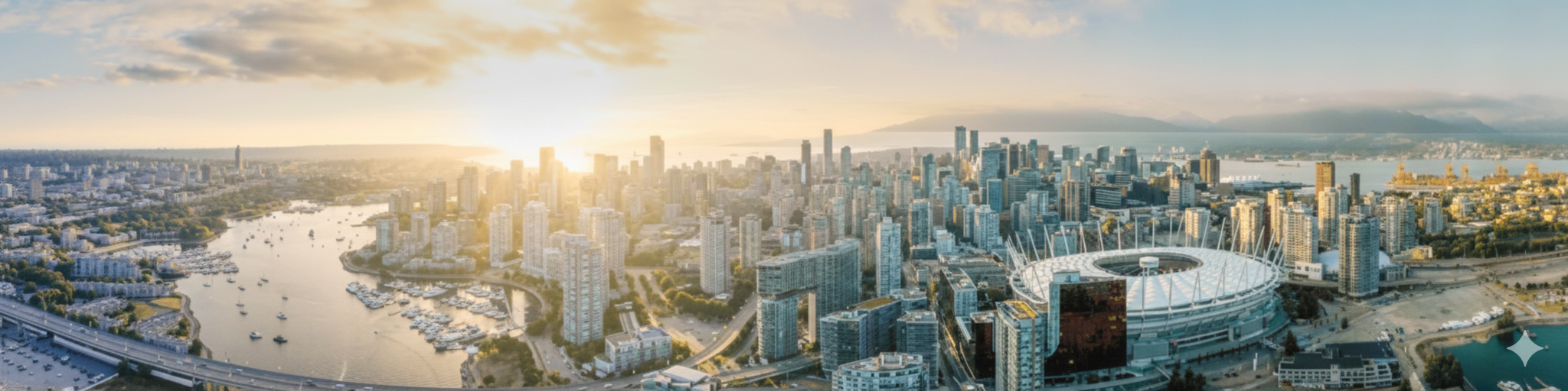 Aerial view of a city skyline at sunset, featuring numerous high-rise buildings, a large stadium, a river with boats, and surrounding greenery.