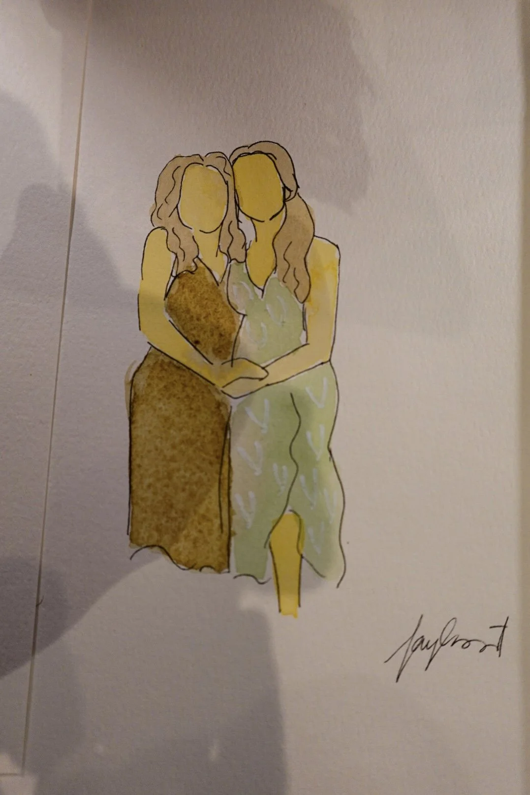 A watercolor sketch of two women standing close together, with their arms around each other, holding a small, blurry object. The woman on the left wears a brown dress, and the woman on the right wears light-colored clothing with patterns.