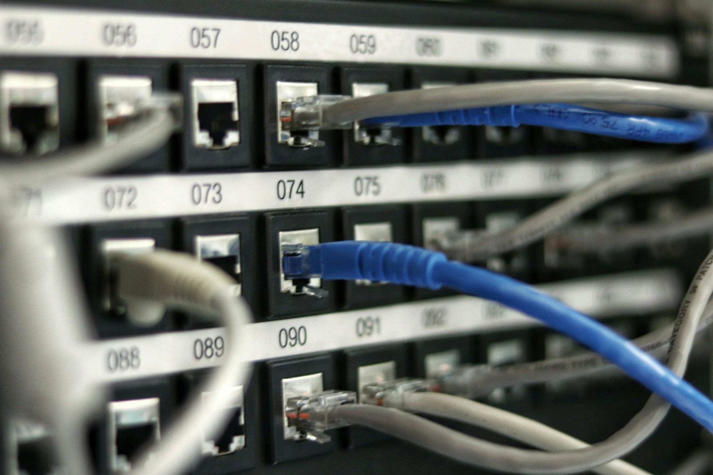 Close-up of a network server rack with Ethernet cables connected to port switches, labeled with numbers.