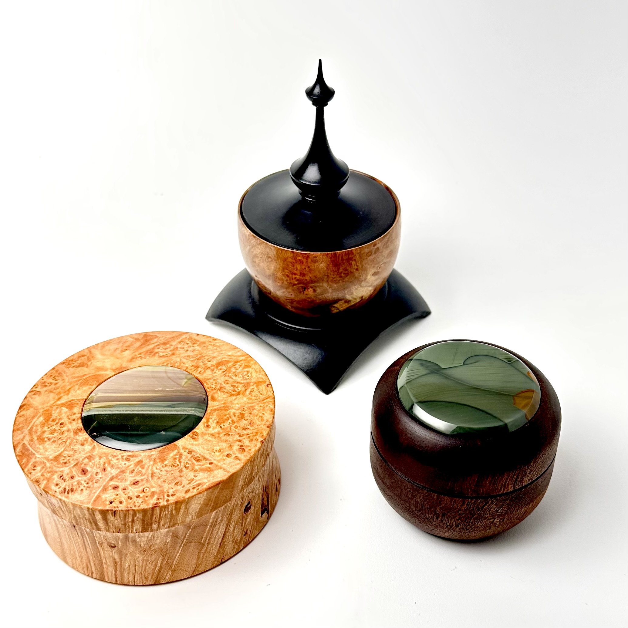 Three decorative boxes with glass inlays, one with a black lid and finial, all on a white background.