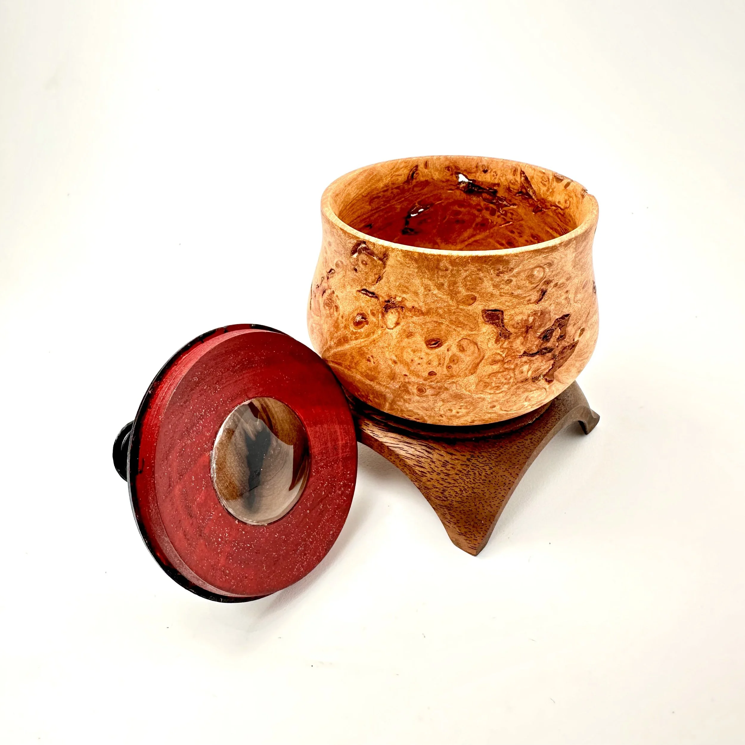 A wooden tea caddy with a lid, resting on a small wooden stand, against a plain white background.