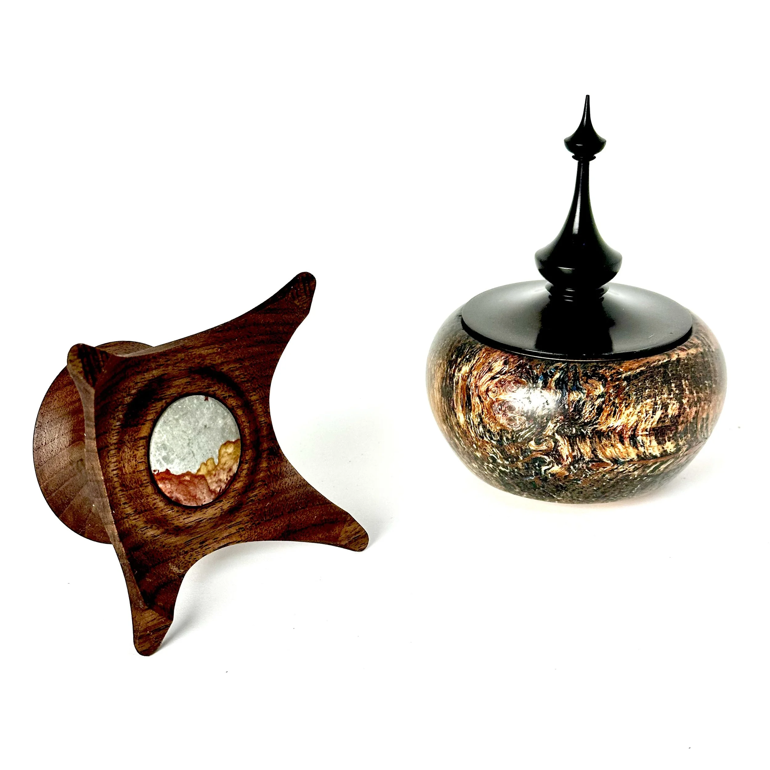 Decorative wooden and ceramic objects on a white background, including a wooden star-shaped piece with a mirror and a round ceramic container with a black lid and tall spire.