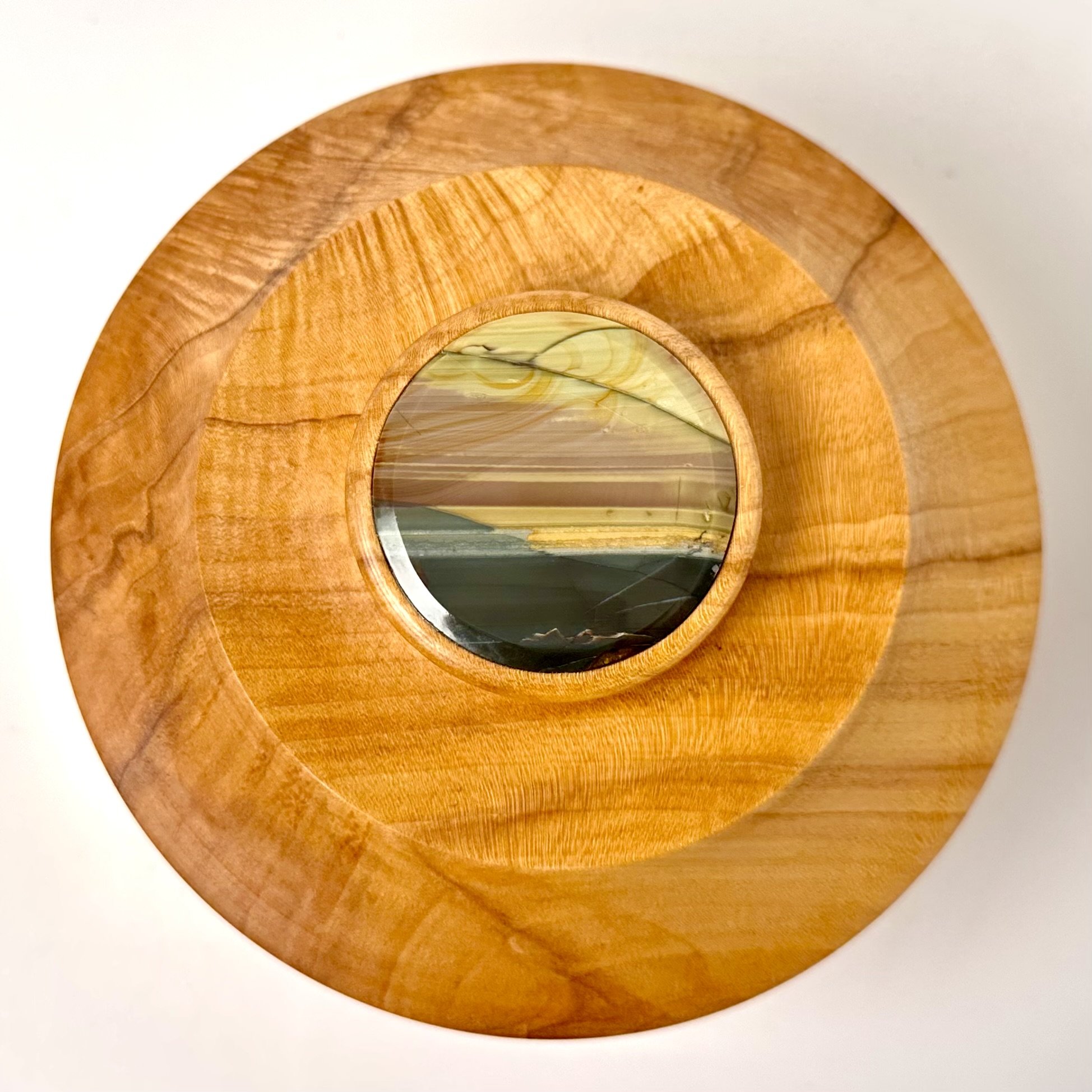 A top-down view of a round wooden piece with a marble-like center embedded in it.