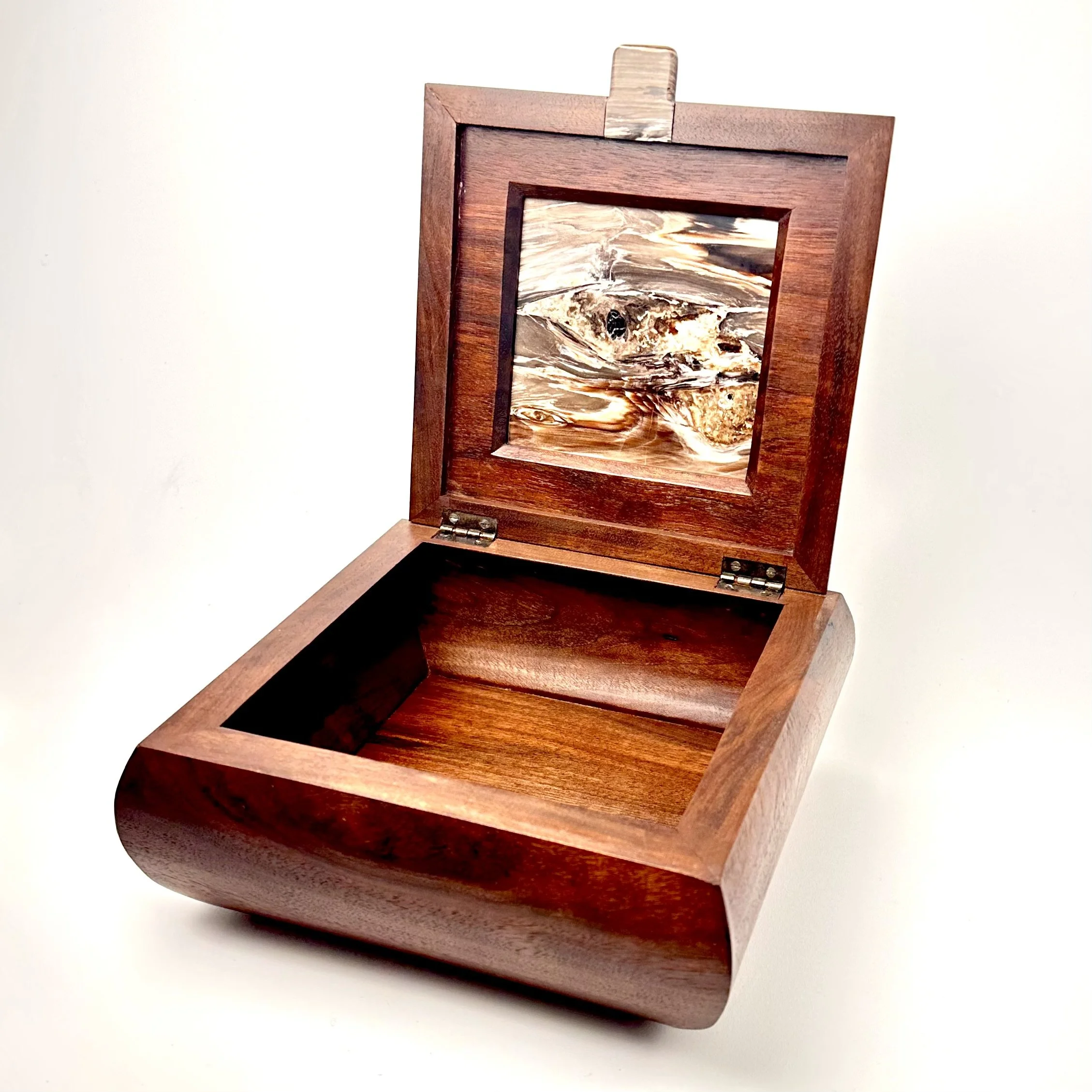 A wooden jewelry box with an open lid, revealing an inlay of 14.5 million year old opalized petrified wood.  The walnut is much, much younger.
