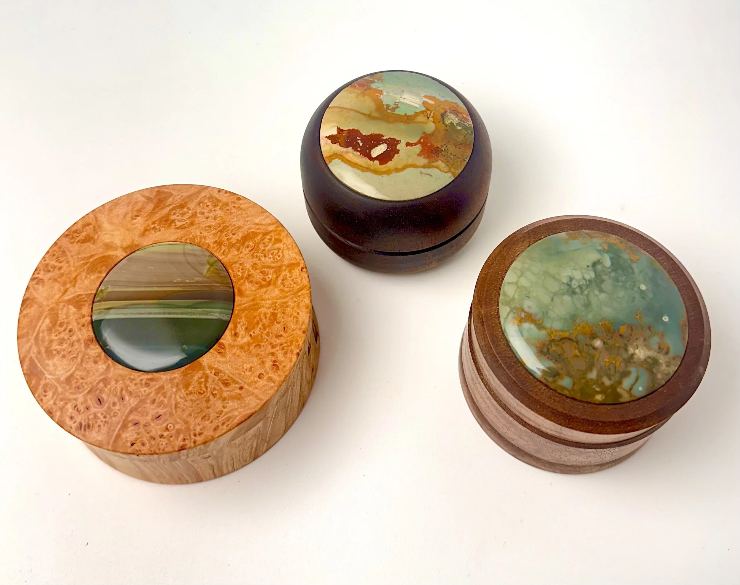 Three decorative wooden boxes with picture jasper inlays including Owyhee picture jaspers and Blue Mountain jasper.  Boxes made from walnut and maple burl. 