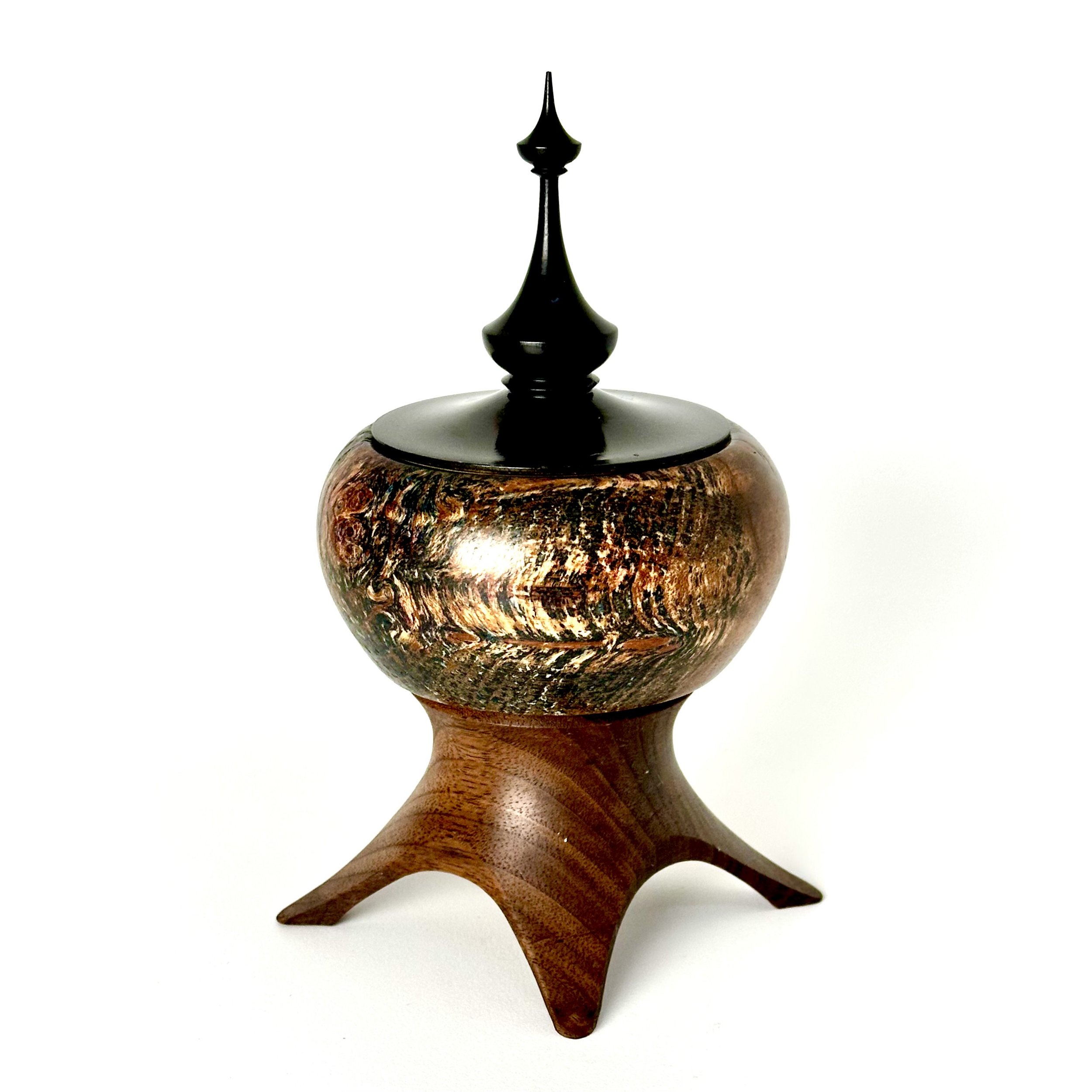 Decorative wooden container with a black lid and finial, elevated on a uniquely shaped wooden stand, isolated on white background.