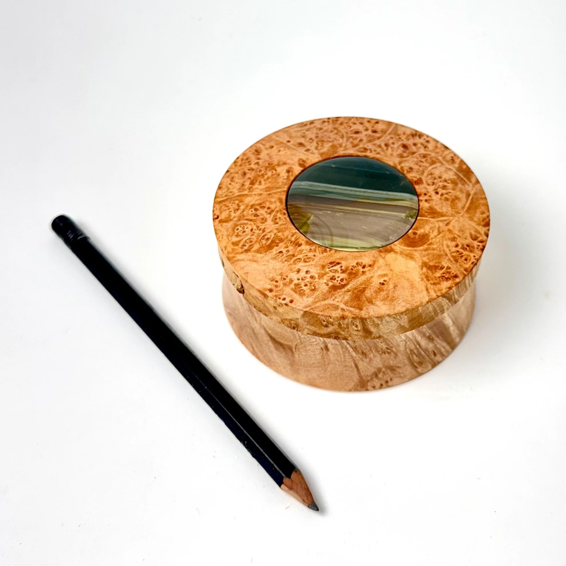 A round wooden object with an orbicular Blue Mountain picture jasper in the center.