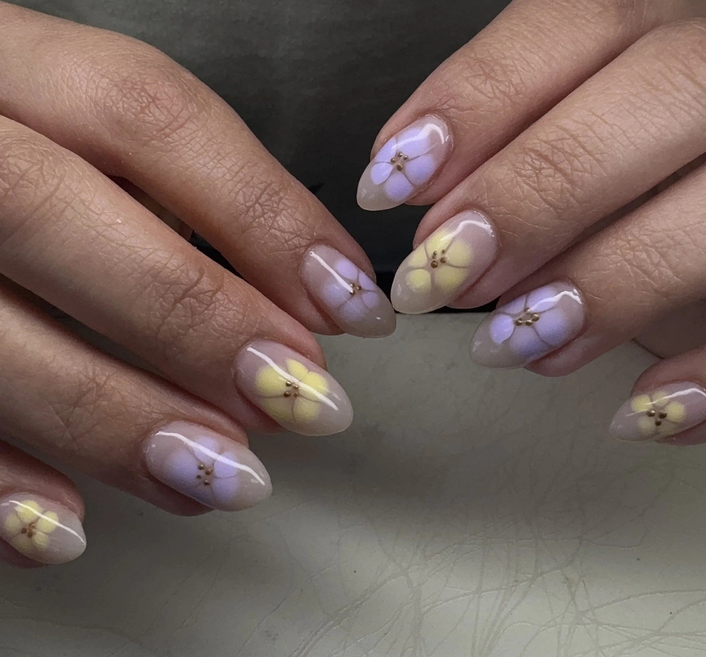 Nail art with pastel-colored flower designs on fingernails.