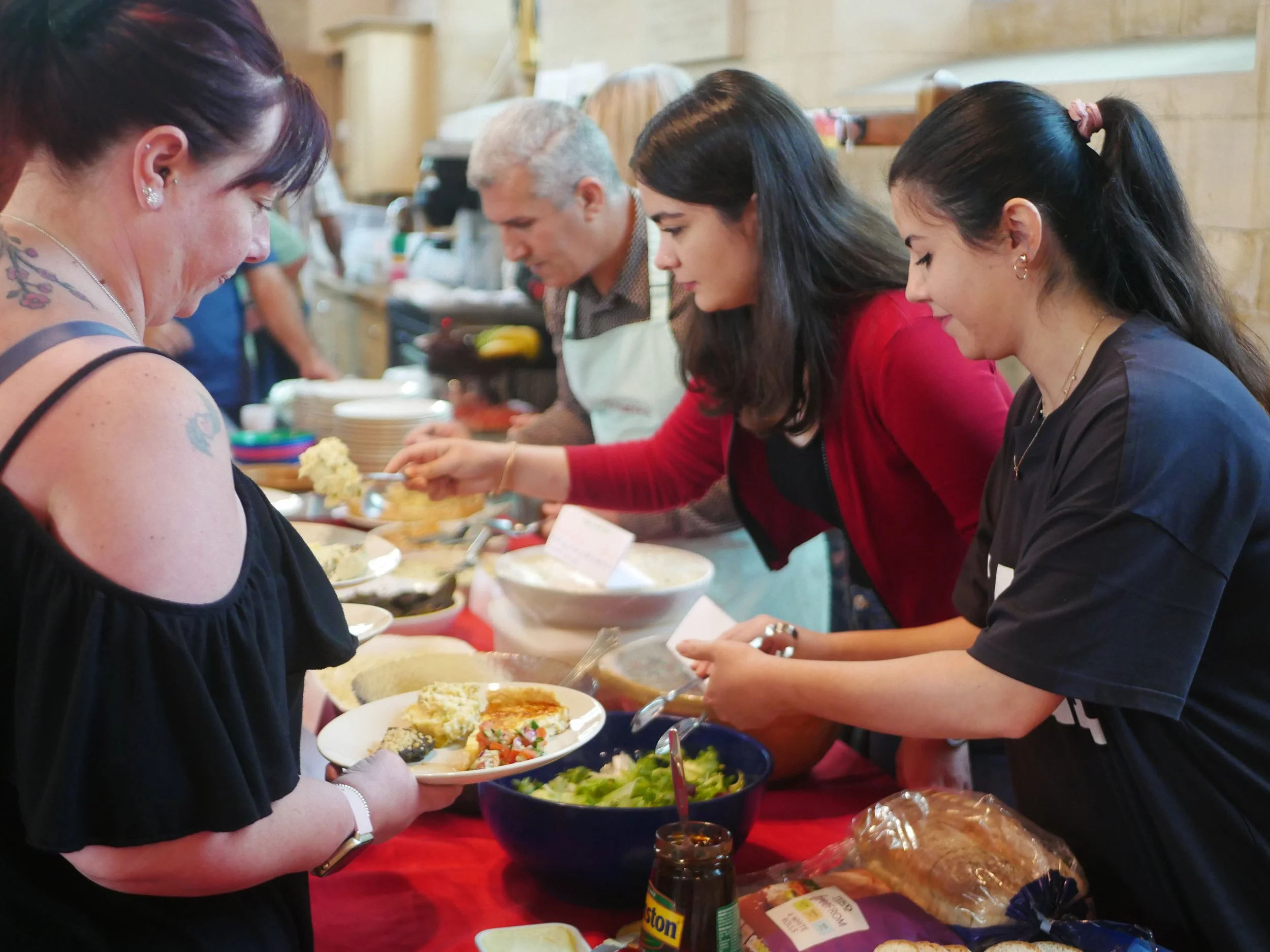 People serving themselves food at a buffet table during a gathering.