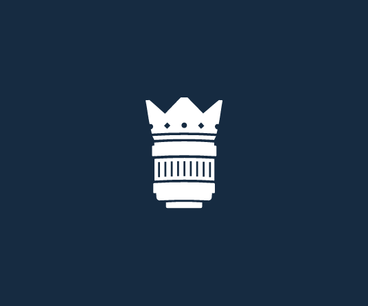 Icon of a white crown and camera lens on a dark blue background.