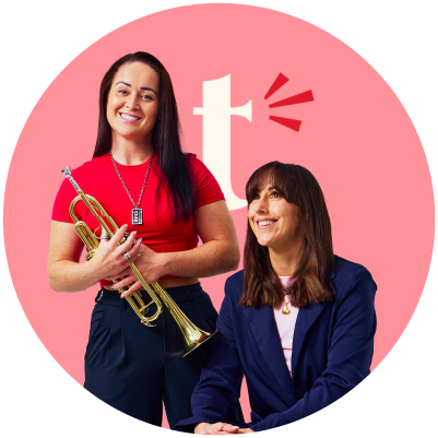 Two women smiling, one holding a trumpet, in front of a pink background with a white logo.
