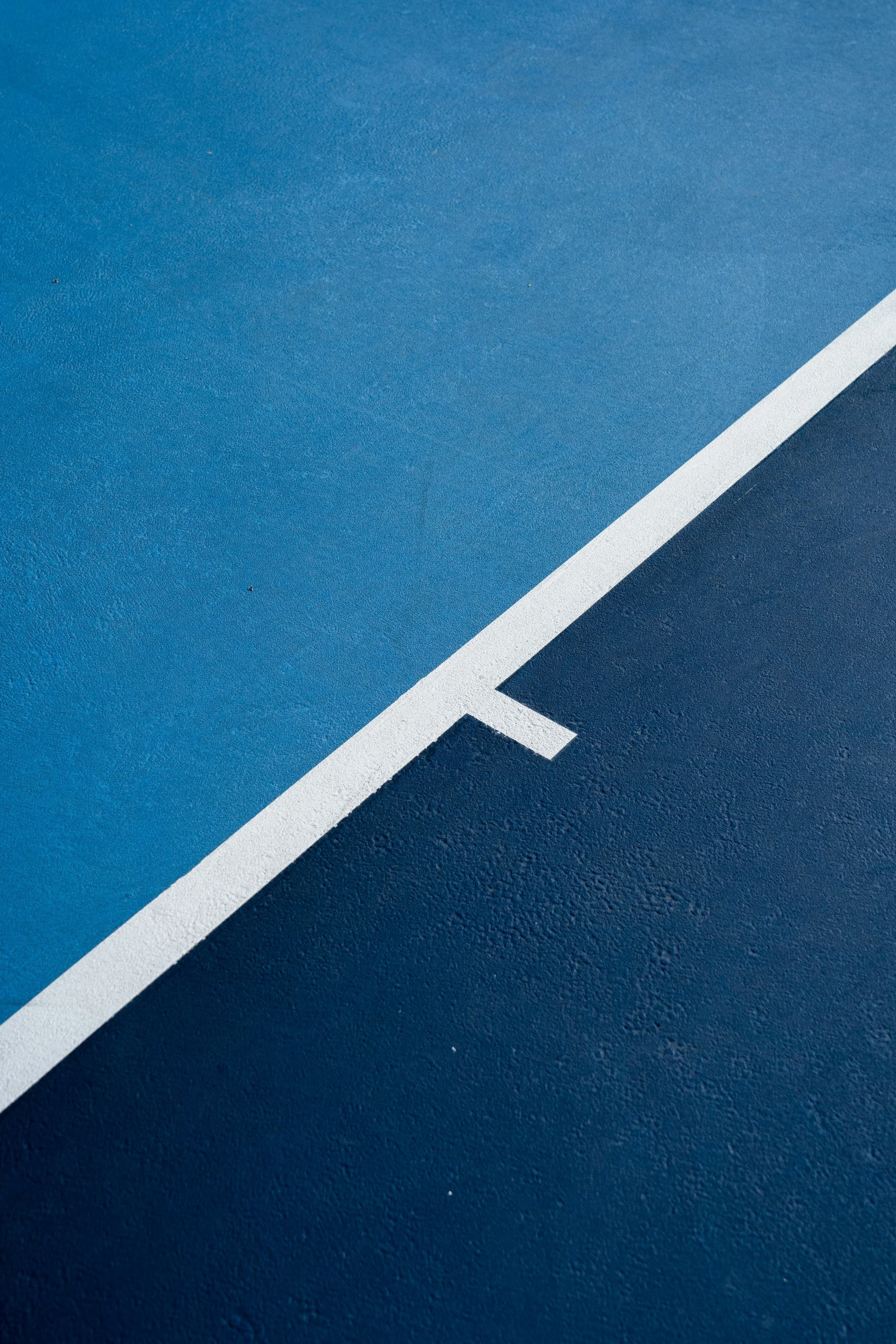 Close-up of a blue tennis court with a white boundary line.