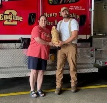 Two people standing in front of a fire truck, holding a eagle.