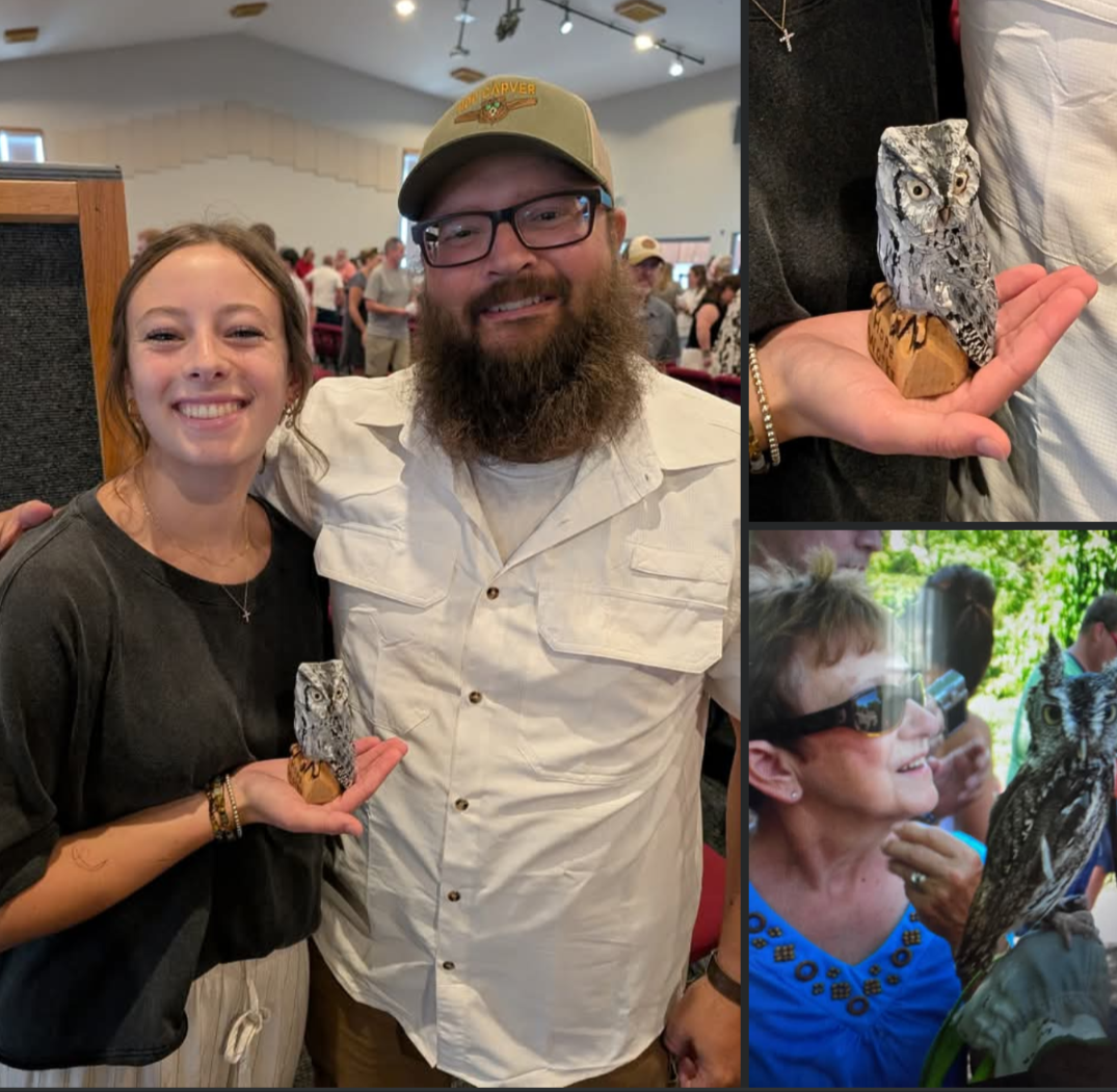 People at an indoor event, with a woman holding a small owl, a man with a beard and glasses smiling, and another woman with sunglasses looking at an owl in her hand.
