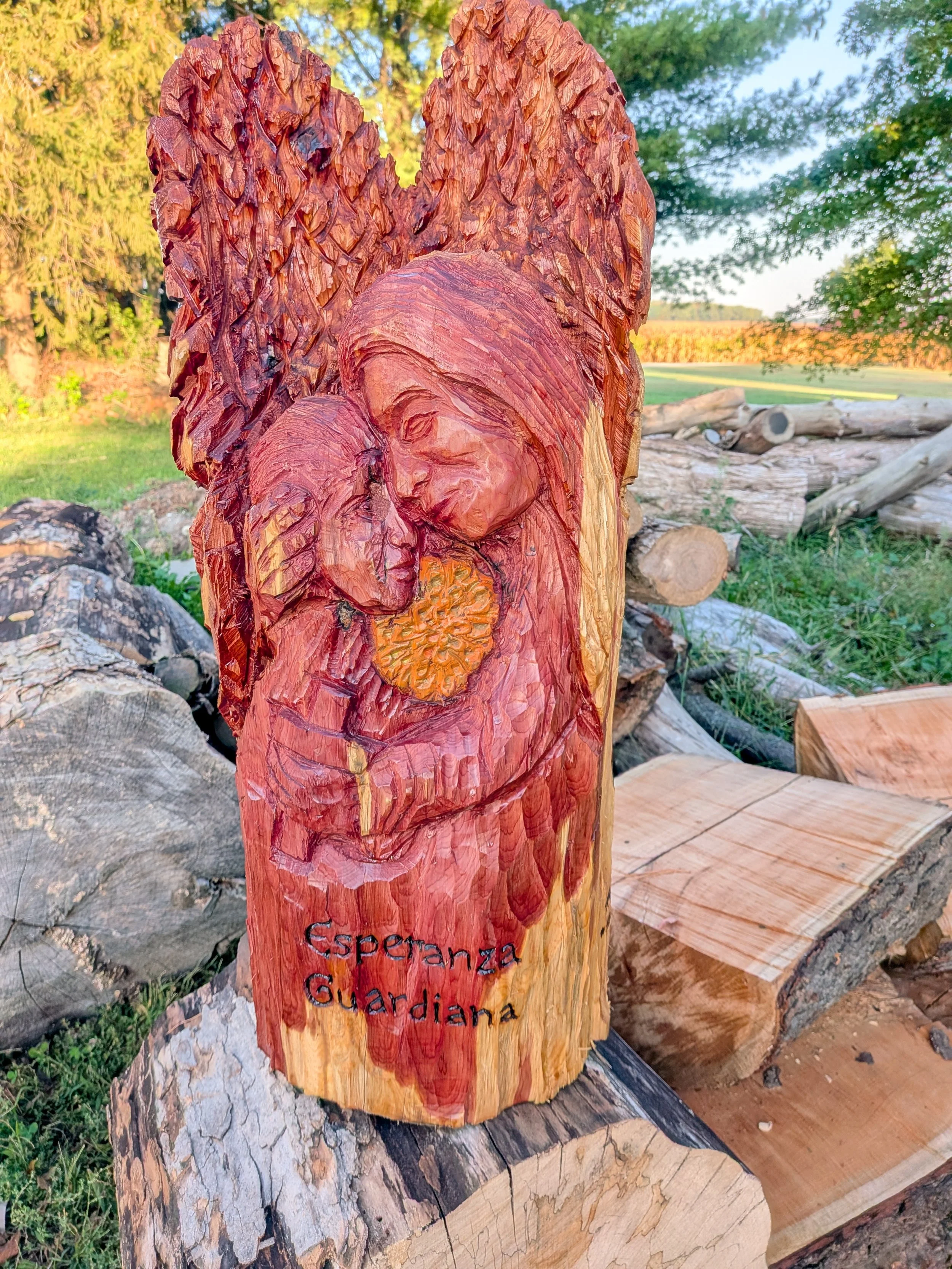 Wood carving sculpture of a woman and a child embracing, with the words "Esperanza Guardiana" engraved below.