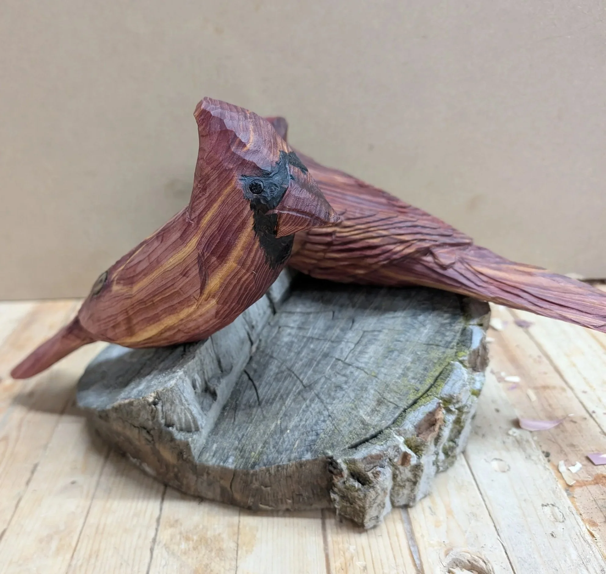 Wooden carved and painted bird sculpture perched on a tree wood base