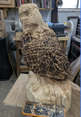 Wooden sculpture of an eagle on a workbench in a workshop.