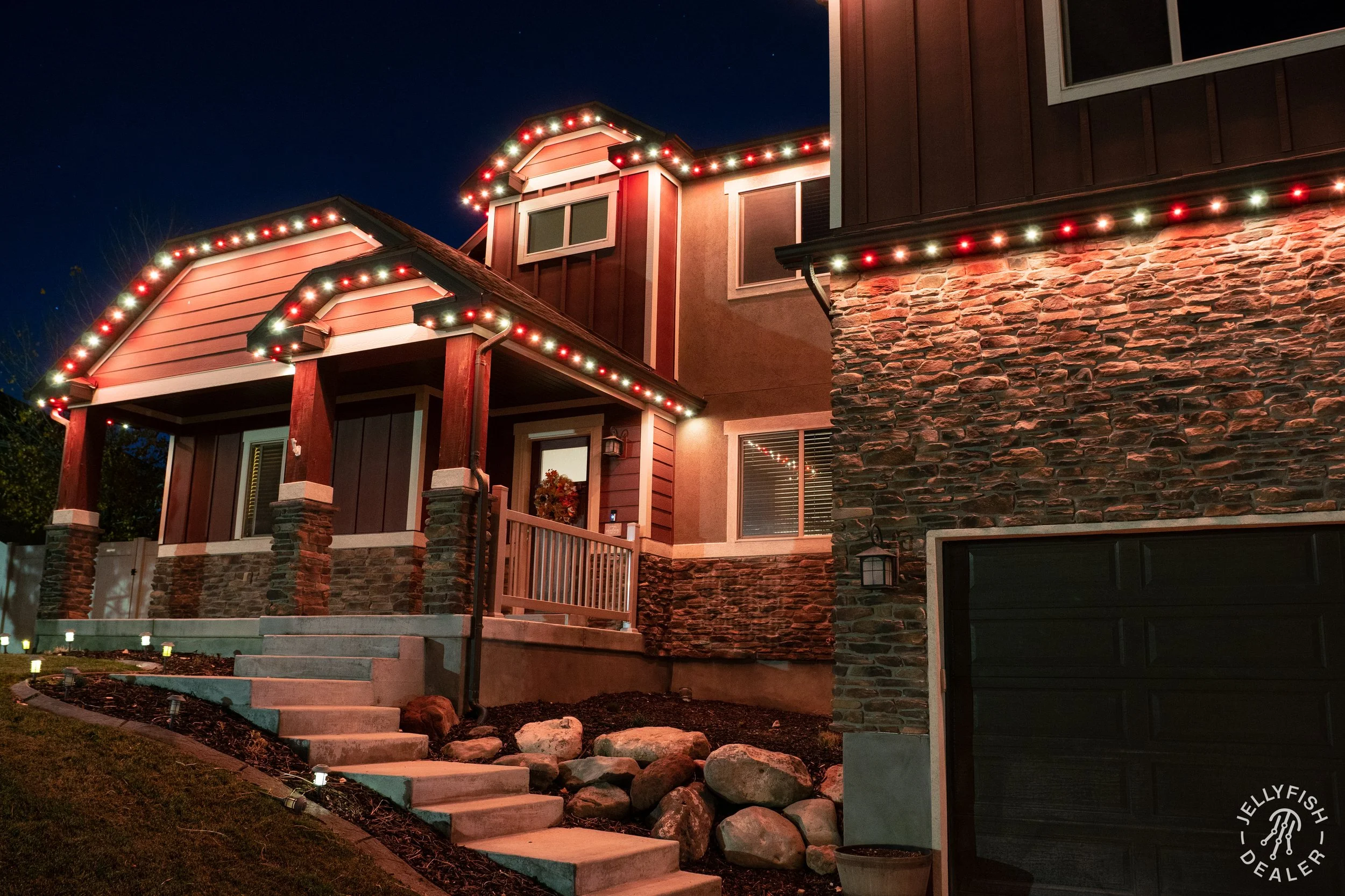 Warm holiday and accent lighting installed along multi-peak rooflines for a welcoming evening atmosphere.