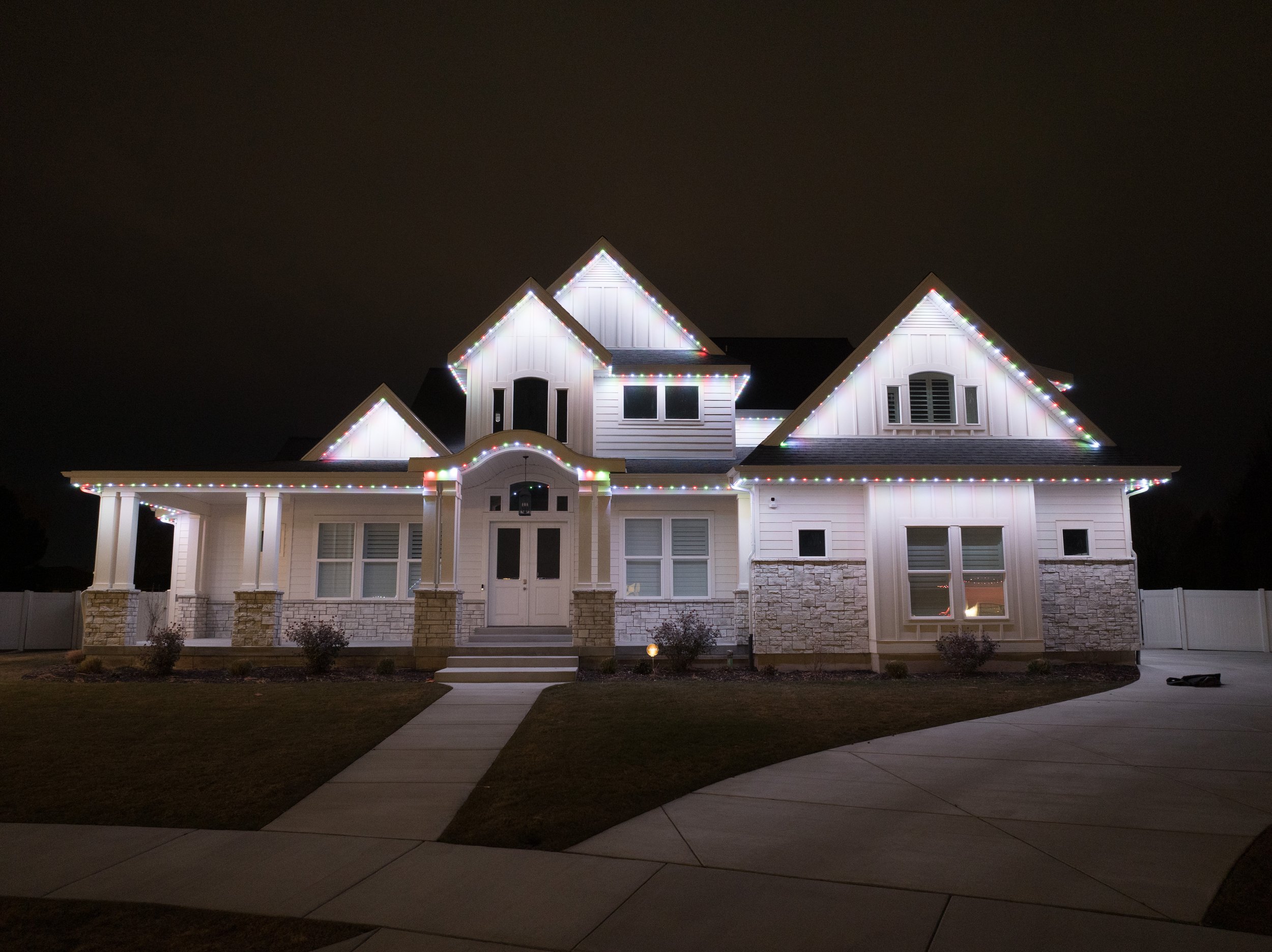Custom permanent track installation featuring vibrant twilight presets and subtle accent lighting to highlight modern stone architecture.