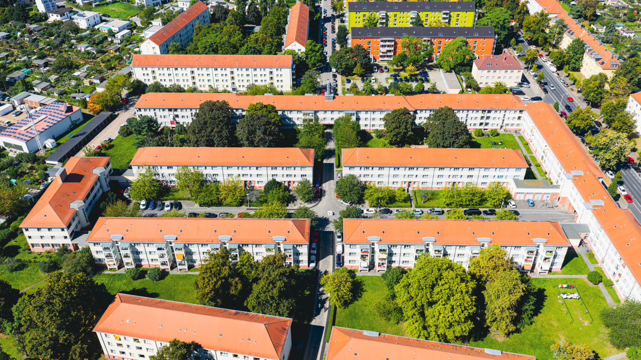 Luftaufnahme eines Wohnviertels mit mehrstöckigen Apartments, grünen Bäumen und Straßen.