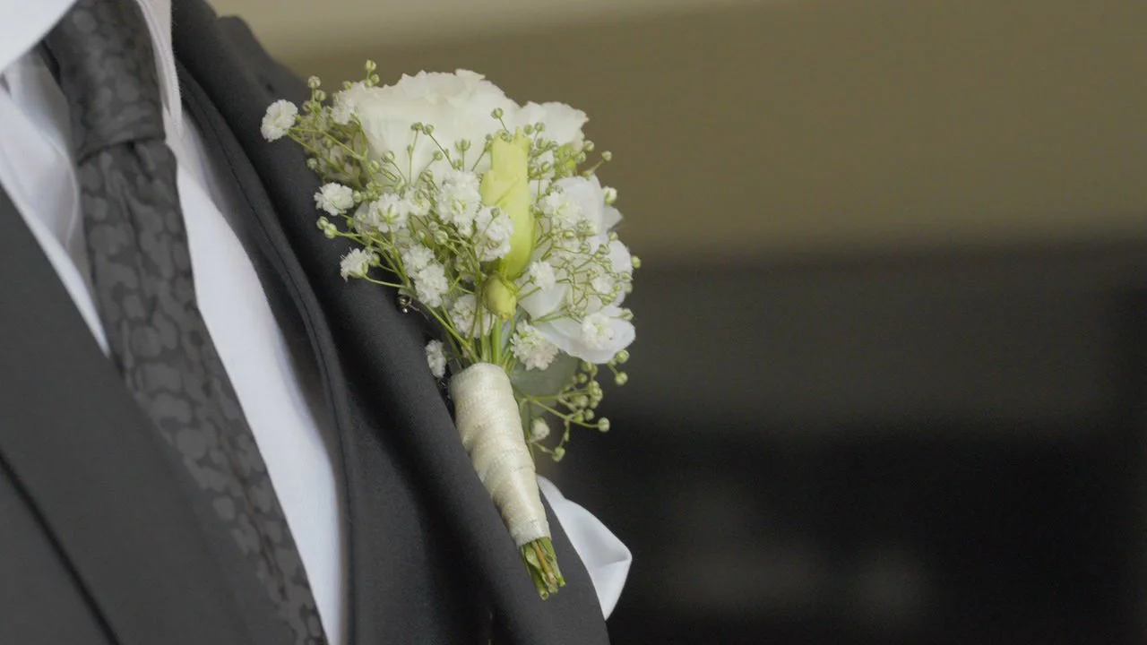 Weiße Hochzeitsblumen am Sakko eines Mannes
