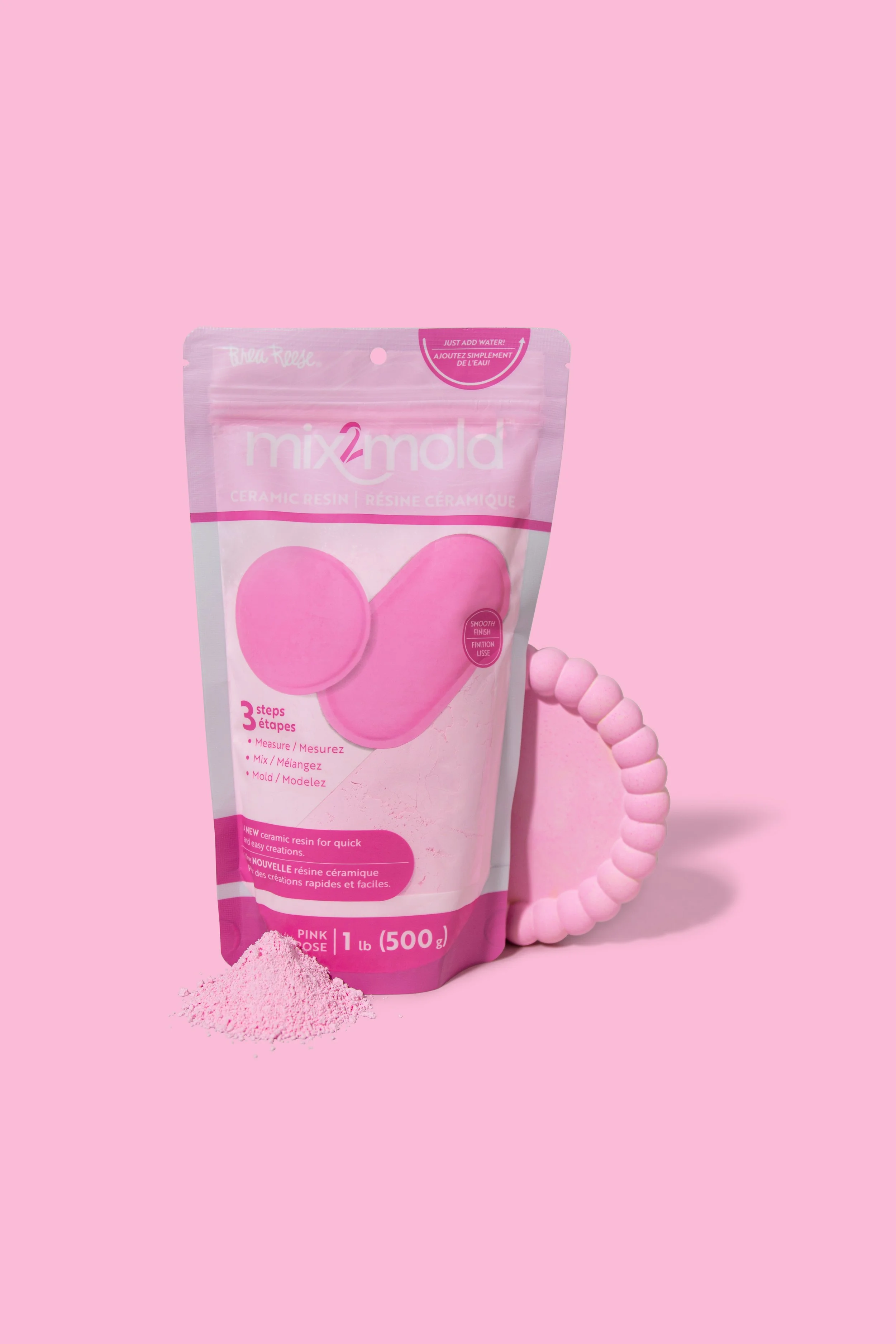 Pink package of mix2mold ceramic resin with pink powder spilled in front, also shown are pink mold and a pink beaded bracelet on a pink background.