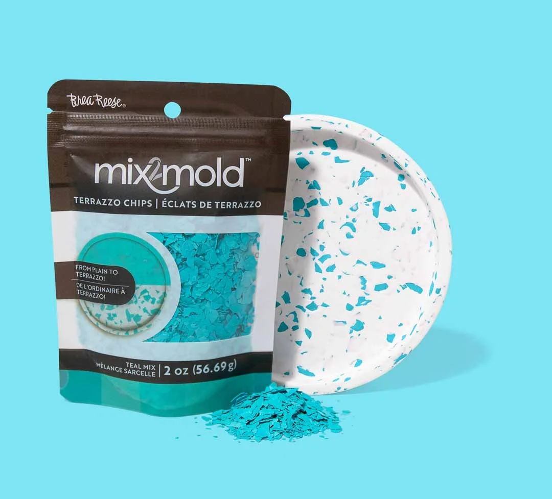 A bag of Mix2Mold terrazzo chips, a terrazzo tile sample, and a small pile of terrazzo chips on a light blue background.
