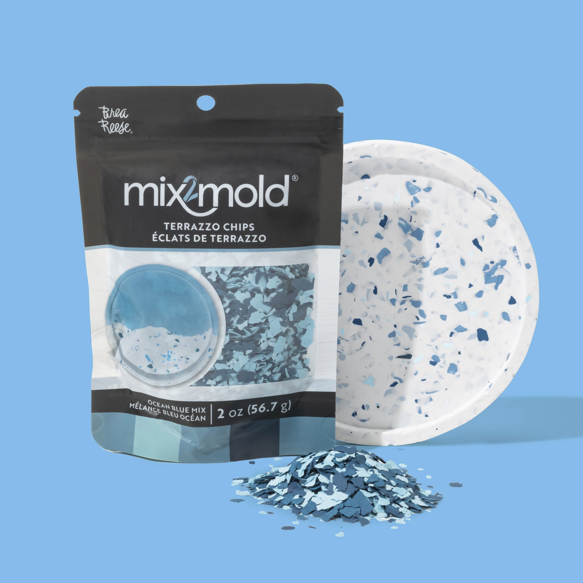 A package of Mix2mold ocean blue terrazzo chips, a terrazzo tile, and a small pile of blue terrazzo chips on a blue background.