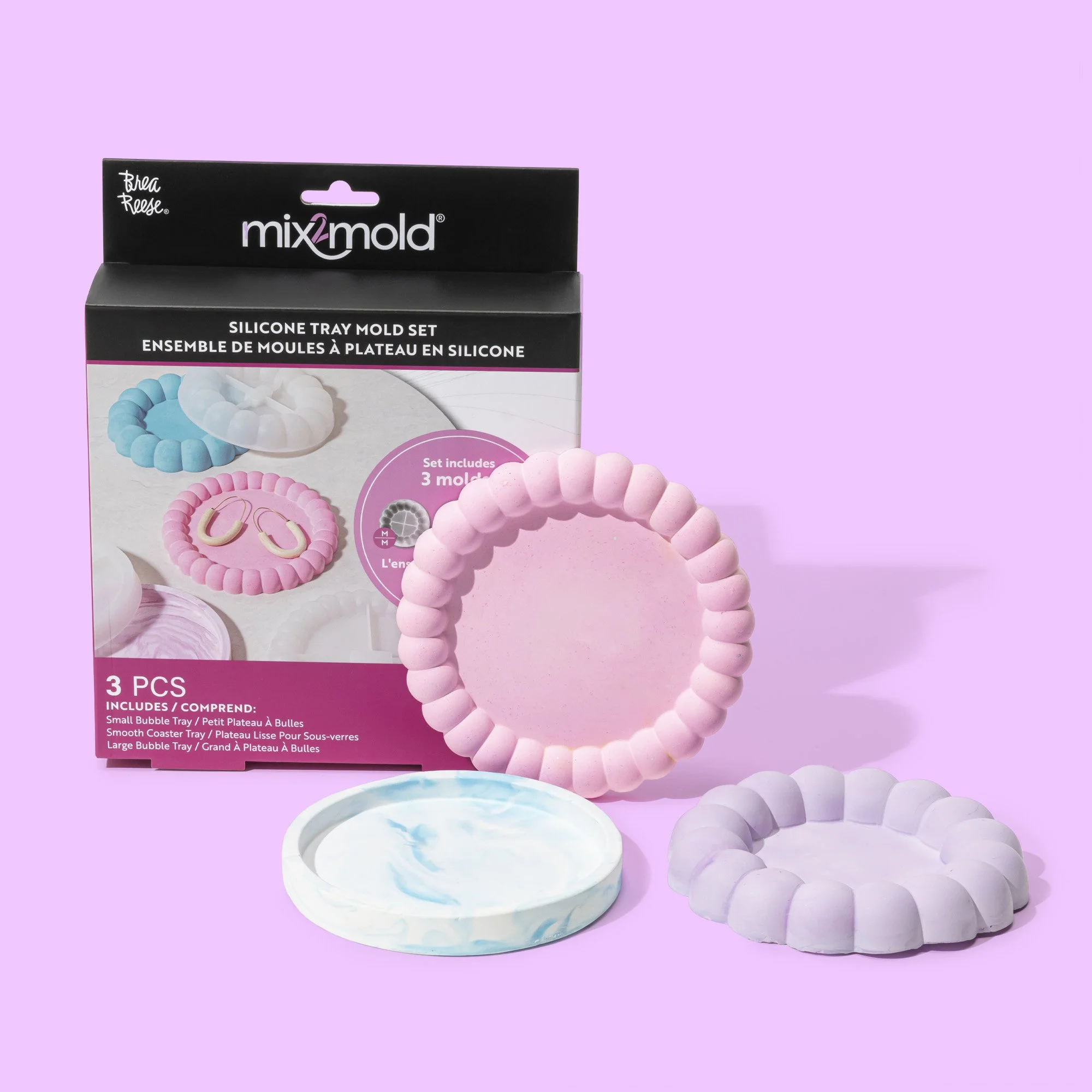 Set of three silicone tray molds in pastel pink, purple, and marble blue, displayed in front of packaging with images of the molds used for jewelry or crafts, on a lavender background.