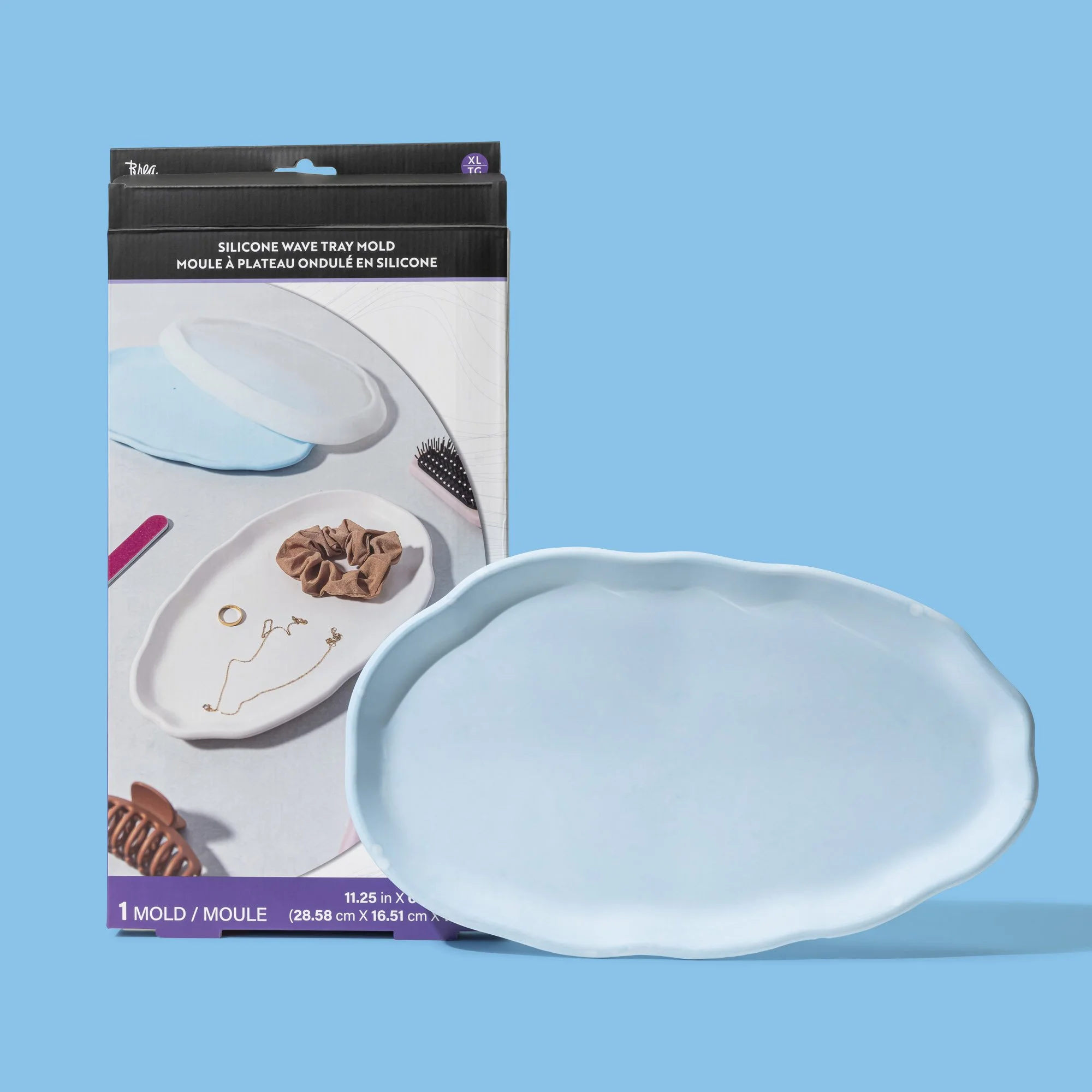 Blue silicone wave tray mold in front of its packaging, which shows the tray used for making an oval-shaped dish.