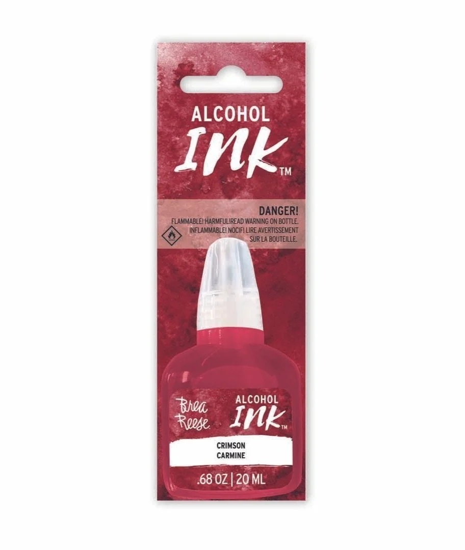 A package of alcohol ink in a red bottle labeled 'Brea Reese Alcohol Ink' in crimson carmine color with a warning label about flammability.