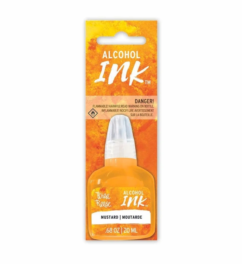 Packaging of alcohol ink in a small bottle, labeled as mustard flavor, with a yellow-orange background and warning labels.