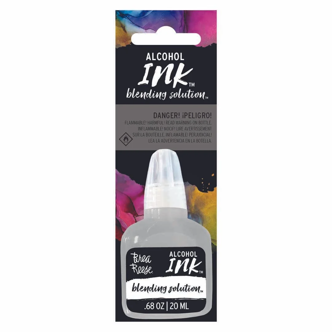A bottle of alcohol ink blending solution in packaging with colorful splashes of ink in the background.