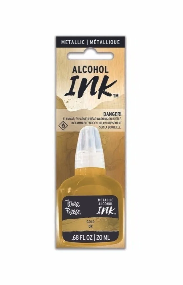 Bottle of metallic gold alcohol ink with a clear cap, packaged in a cardboard backing with printed labels, including warning signs and product details.
