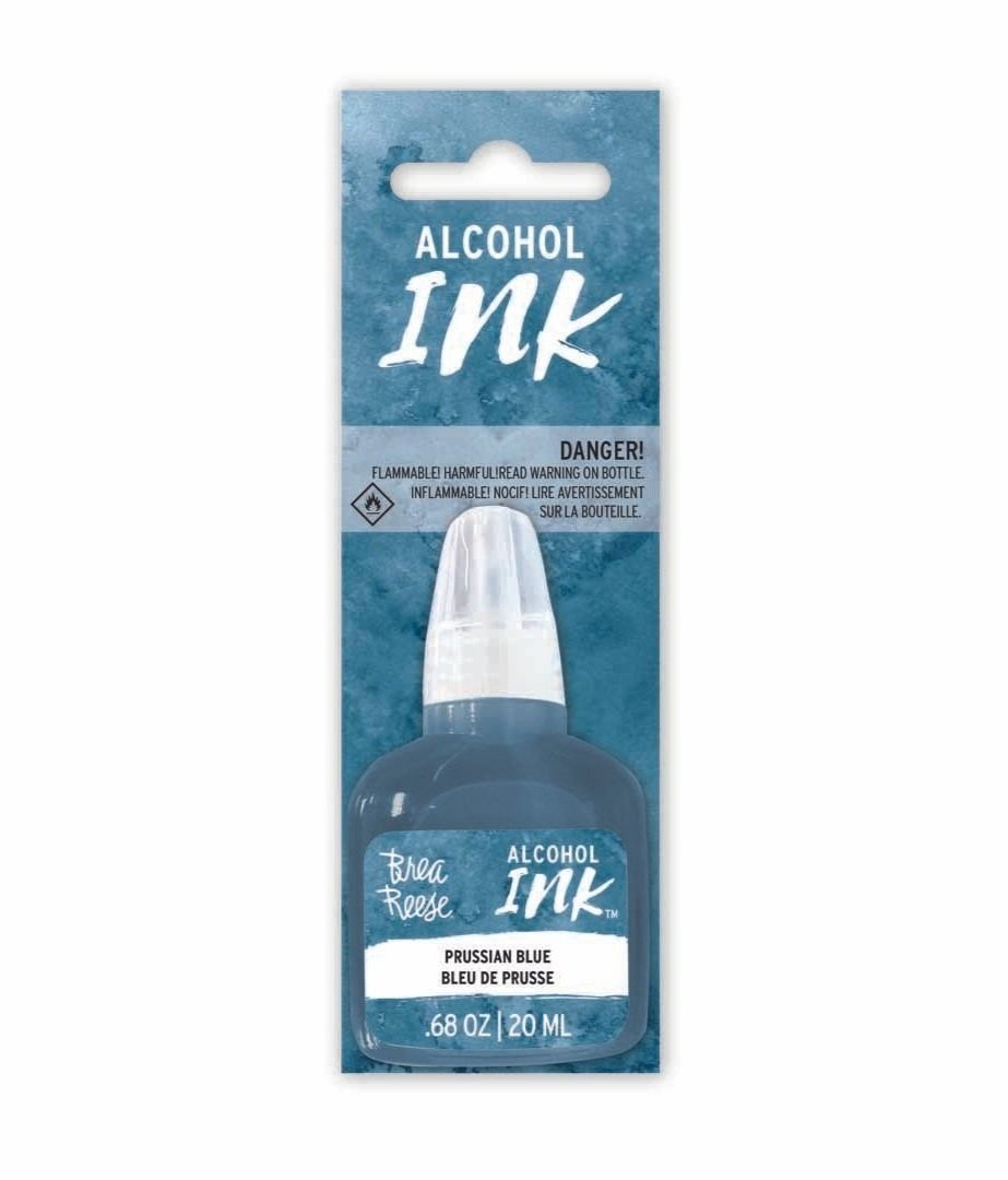 A bottle of alcohol ink in Prussian blue color, labeled Brea Reese, with a warning about flammability on the packaging.